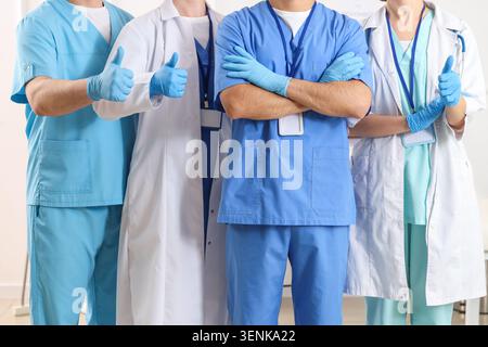 Medical team collaboration and healthcare success, doctors and nurses in scrubs and lab coats with thumbs up Stock Photo