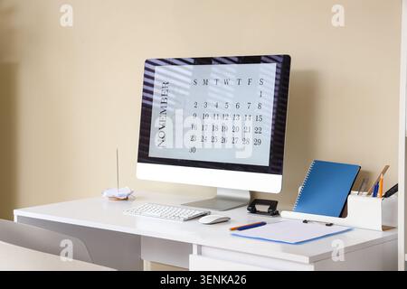 November 2027 calendar displayed on modern computer monitor on white office desk with stationery, the monitor sits on a clean white office desk Stock Photo