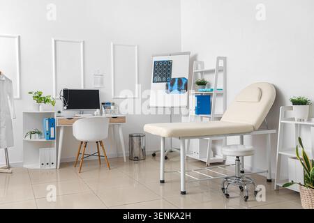 Modern medical examination room interior with doctors desk, computer, stethoscope, and patient examination couch Stock Photo