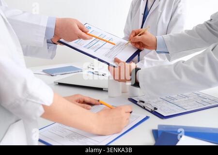 Medical professionals collaborating on patient records, healthcare team reviewing documents, doctors discussing treatment plans, hospital administrati Stock Photo