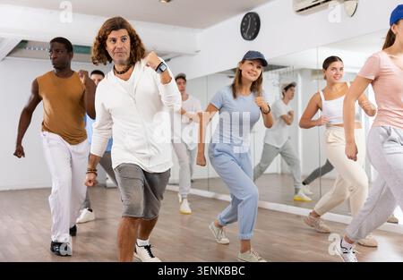 Excited sporty multiracial people practicing new movements steps during dancing training in studio Stock Photo