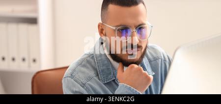 Focused young man in eyeglasses working on computer reflecting data and information on screen business and technology, this image business technology Stock Photo