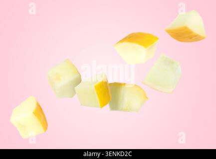 Sweet melon pieces flying in air against pink background Stock Photo