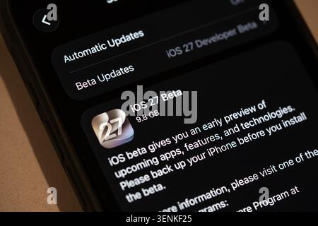 Close-up of an iPhone screen displaying iOS 27 beta update information in the settings menu, including automatic updates and developer beta options Stock Photo