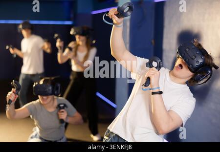 Emotional teenager in VR headset immersed in virtual reality game Stock Photo