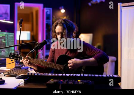 Musician with condenser microphone creating a song on guitar, working on mixing and mastering tunes, with artist audio engineer recording music and adding sound effects in post production, acoustics. Stock Photo