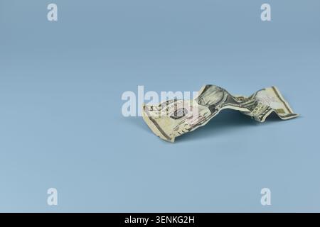 Crumpled five dollar bill on smooth blue surface for economy and money concept Stock Photo