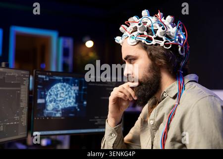 Programmer using EEG headset to upload his mind into computer, attaining immortality, with neuroscientist in apartment experimenting with transferring consciousness into cyberspace. Stock Photo