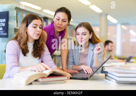 Three female friends studying together at library Stock Photo