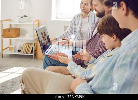 Family With Children Using Laptop At Home For Online Video Call Stock Photo