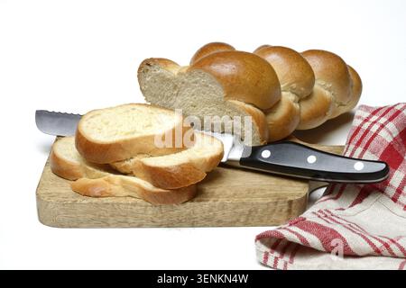 Sliced butter braid with bread knife on wooden board Stock Photo