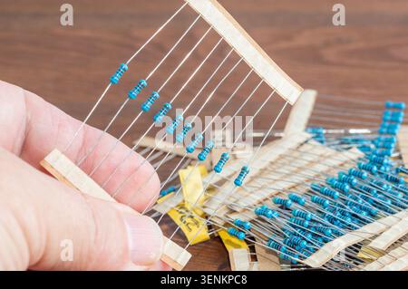 Resistors held in a hand against the background of a wooden table. Stock Photo