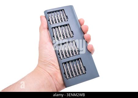 Close up of repair specialist hand holding a compact case with many interchangeable screwdriver bits isolated on white background Stock Photo