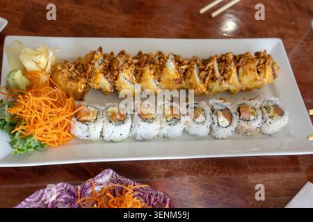A horizontal, high-angle shot of an assorted sushi platter, showcasing a diverse combination of deep-fried tempura rolls and classic sesame-crusted sa Stock Photo