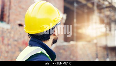 Architect, man and helmet with building inspection on construction site for safety regulations. Male person, contractor or civil engineer checking Stock Photo