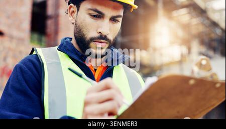Architect, writing or man with clipboard for building inspection or safety on construction site. Male person, contractor or civil engineer with Stock Photo