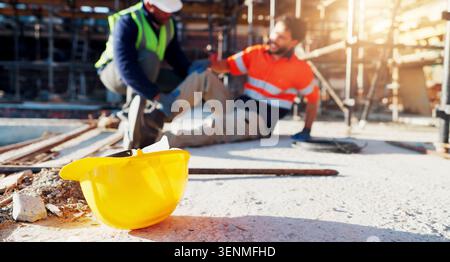 Hardhat, injury and construction workers on site with accident, fall or leg fracture outdoor. Muscle sprain, men and engineers with helmet for safety Stock Photo