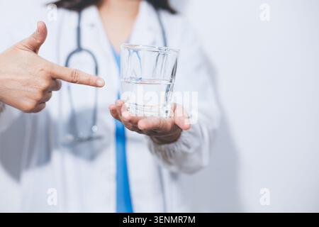 Portrait of Asian doctor woman standing holding coffee cup in white studio background Stock Photo