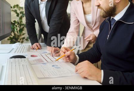 Business team analyzing financial charts at desk with pencils and computer Stock Photo