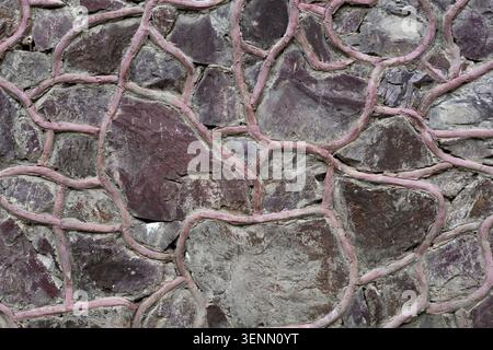 Dark stone wall texture with decorative pink mortar joints. Stock Photo