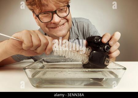 Crazy technician cleaning digital camera bad way in water Stock Photo