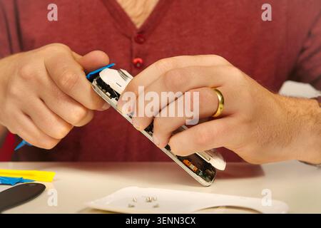Man working on repairing of broken smartphone with zoom lens Stock Photo