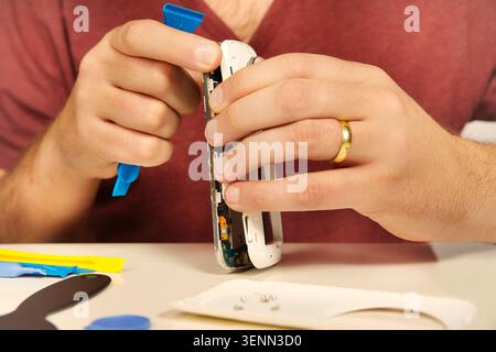 Man working on repairing of broken smartphone with zoom lens Stock Photo