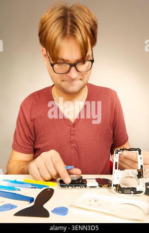 Man working on repairing of broken smartphone with zoom lens Stock Photo