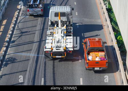 Construction work is underway on a bustling city street as a large truck and an orange delivery vehicle navigate their way past roadwork. Stock Photo