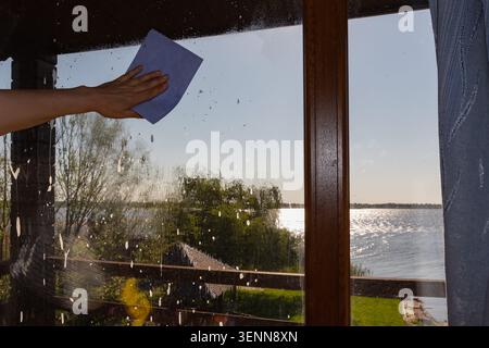 Woman Cleaning Large Window Glass With Cloth And Soap Foam Stock Photo