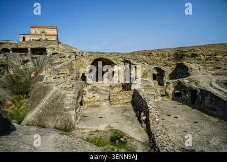 A panoramic view showcases the ancient Uplistsikhe rock-hewn town, featuring numerous caves, tunnels, and remnants of old structures carved into the s Stock Photo
