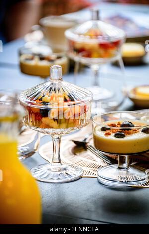 Elegant glass with fresh fruit salad and yogurt with blueberries and granola at an upscale breakfast table. Food styling. Stock Photo