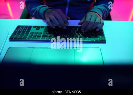Hands Typing on Keyboard Under Neon Light Stock Photo