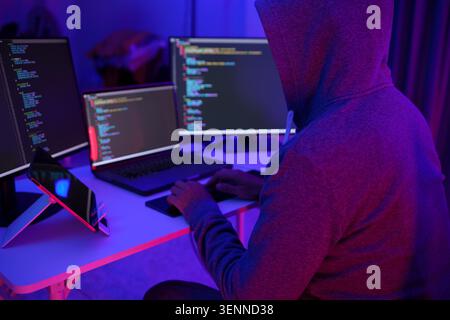 Hacker Coding at MultiMonitor Desk in Neon Light Stock Photo