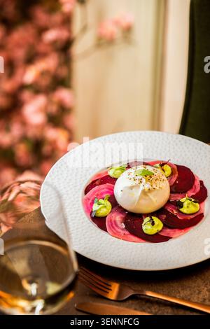 A fresh burrata cheese served over sliced beetroots with herb sauce dollops. Stock Photo