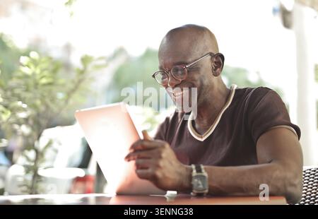 Happy senior man using digital tablet at an outdoor cafe Stock Photo