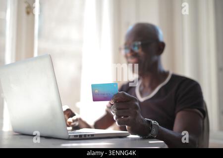Smiling mature man pays online with credit card Stock Photo