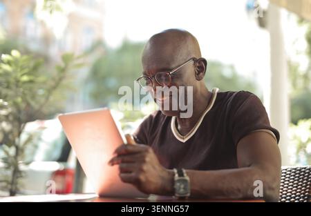 Smiling senior Black man using a tablet outdoors Stock Photo