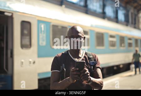 Happy man using smartphone at a train station Stock Photo