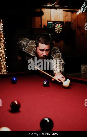 Focused man with beard lining up a pool shot Stock Photo