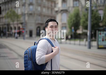 Happy young Asian man with a backpack in the city Stock Photo
