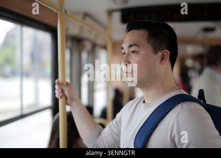 Young Asian man looking out a bus window Stock Photo
