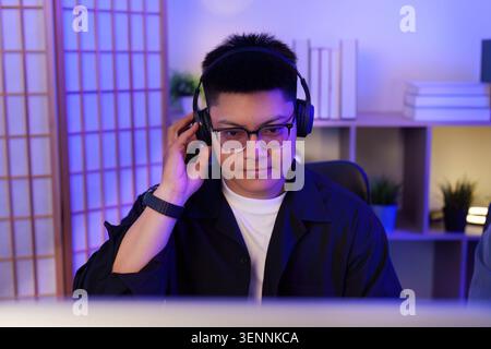 Asian man gamer focused with headset on computer for online gaming streaming and esports technology Stock Photo