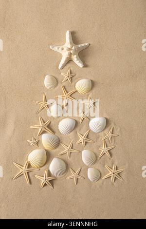 Creative alternative Christmas tree made of seashells and starfish on sandy background. Beach and holiday themes, coastal festive feel. Stock Photo