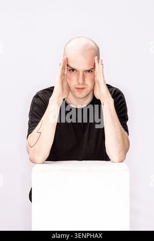 Portrait of Poet and Writer Andrew McMillan. He wearing black trousers and t-shirt with a tattoo on his arm and has a shaved head Stock Photo