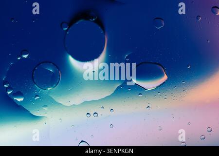 Macro shot of fluid dynamics showing floating oil drops over vibrant, colorful light leaks Stock Photo