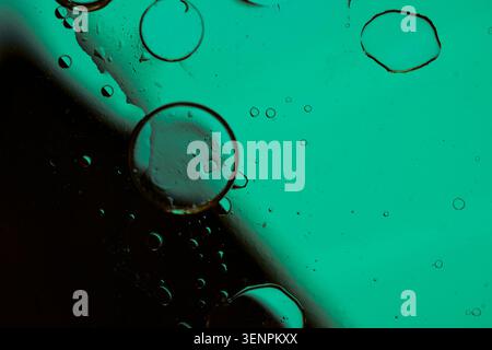 Macro shot of fluid dynamics showing floating oil drops over vibrant, colorful light leaks Stock Photo