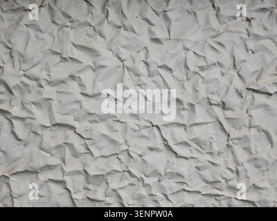 Abstract background texture of crumpled white paper or wrinkled light gray concrete surface with fine speckles and sharp creased folds. Stock Photo
