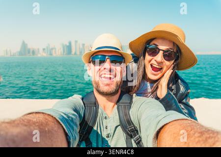 Joyful heterosexual happy couple looking at camera pose smile show happiness taking selfie photo laughing enjoying vacation in DOHA, Qatar. Connection Stock Photo
