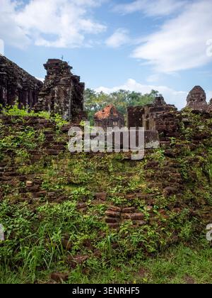Vertical view of the ancient moss-covered brick ruins of My Son Sanctuary in Vietnam under a partly cloudy sky. Danang Vietnam Stock Photo
